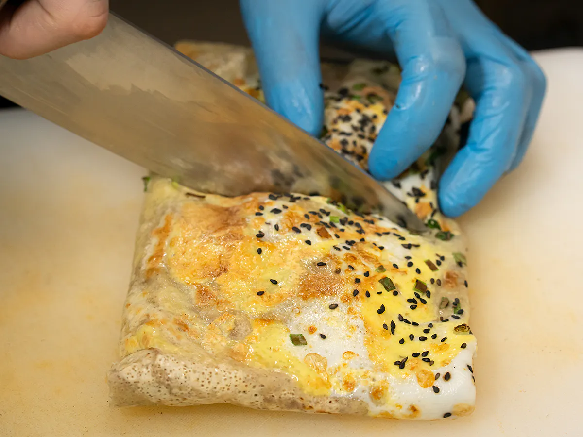 Fresh handmade egg crepe being cut with sharp kitchen knife at Endless Art And Food, an Asian Fushion Restaurant in Catskill