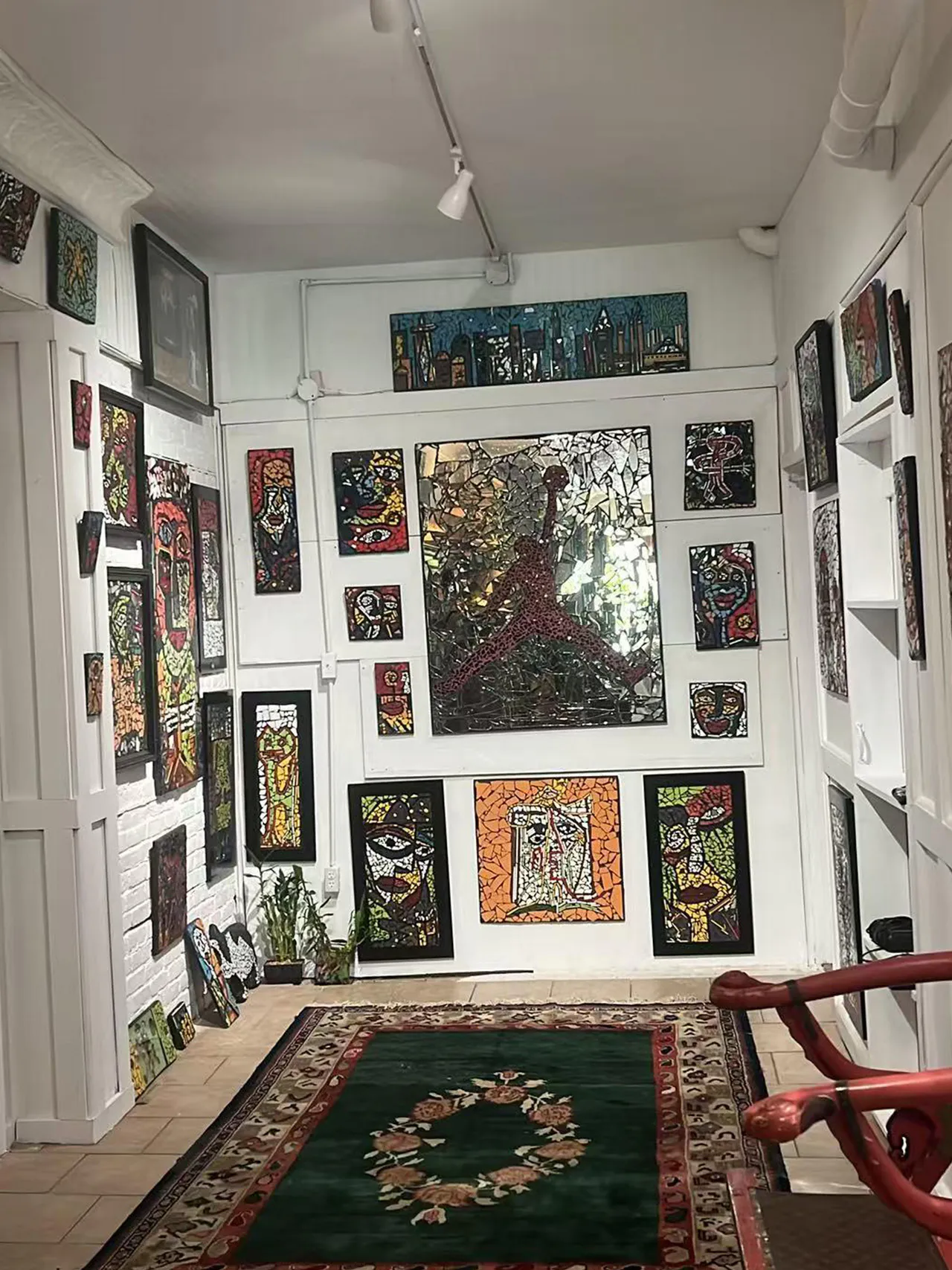 Mosaic art gallery space with colorful framed works and central Jordan-themed piece on white walls at Endless Art And Food, an Asian Fushion Restaurant in Catskill