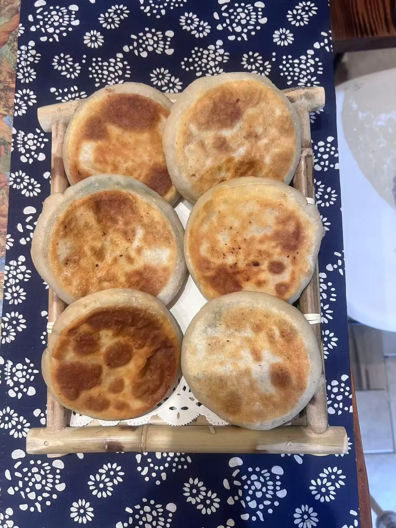 Pan-fried stuffed buns with golden crispy tops arranged on bamboo tray with lace liner at Endless Art And Food, an Asian Fushion Restaurant in Catskill